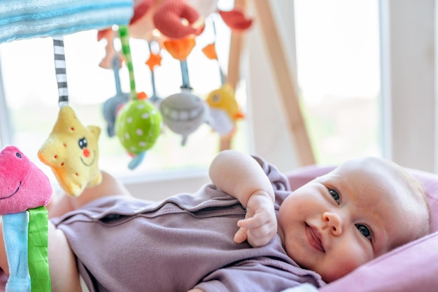 Retrato de um bebê fofo com brinquedos suspensos no fundo