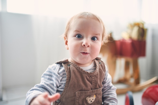 Retrato de um bebê fofo de 1 ano de idade, sentado no chão.