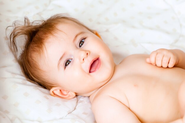 Retrato de um bebê fofo de 6 meses deitado sobre um cobertor. bebezinho feliz