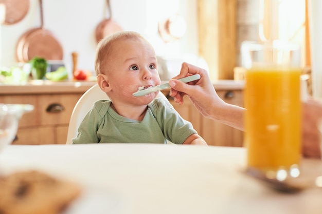 Foto retrato de um bebê fofo que é alimentado por sua mãe de uma colher