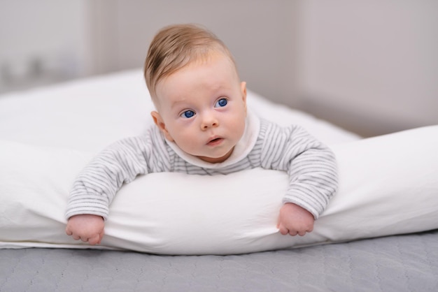 Retrato de um bebê rastejando na cama em seu quarto Bebê fofo deitado de bruços no cobertor macio