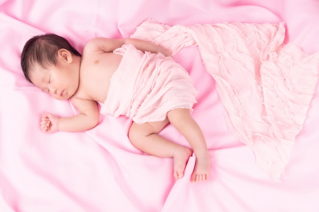 Retrato de um bebê recém-nascido dormindo, um mês de idade em um cobertor rosa. Recém-nascido de moda de estúdio de retrato de conceito.