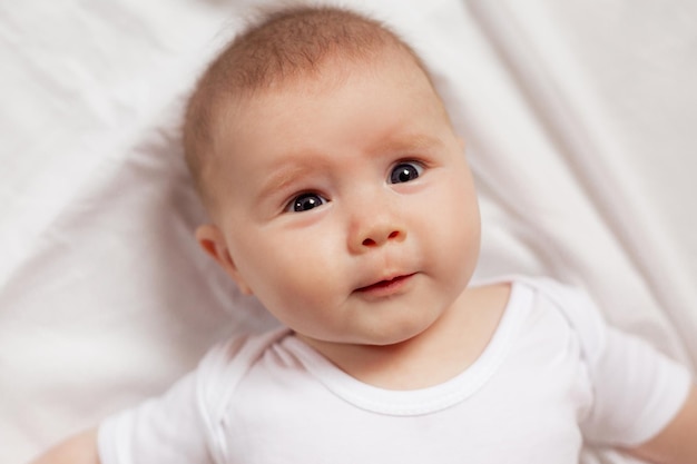Retrato de um bebê recém-nascido sorridente bonito em uma roupa branca em um fundo branco close-up. produtos para crianças. conceito de infância feliz e maternidade. cuidados infantis. Foto de alta qualidade