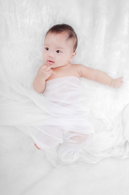 Foto retrato de um bebezinho fofo em uma cama de pele branca