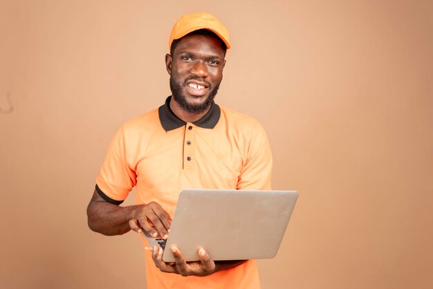 Retrato de um belo homem africano rindo trabalhando com um laptop