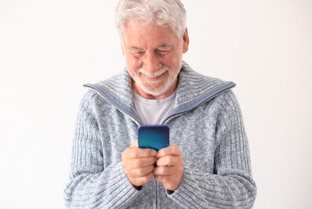 Retrato de um belo homem barbudo sênior isolado em fundo branco usando telefone celular sorrindo