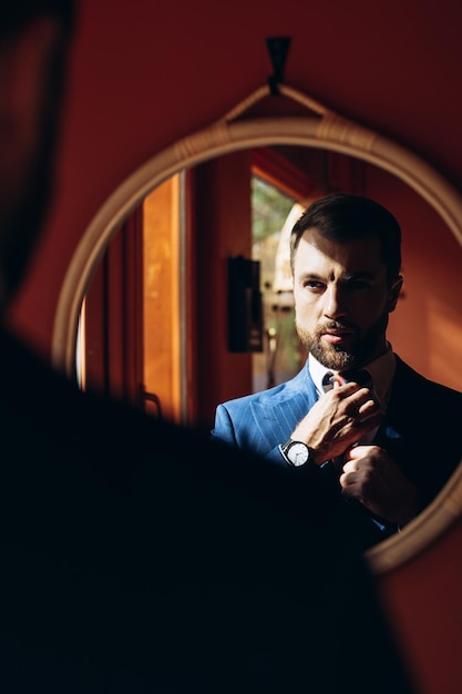 Foto retrato de um belo homem de negócios vestindo um terno azul marinho olhando para o espelho