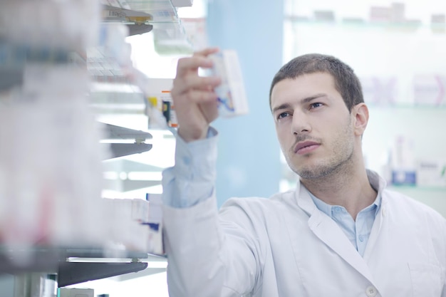 Foto retrato de um belo jovem farmacêutico farmacêutico de pé na farmácia