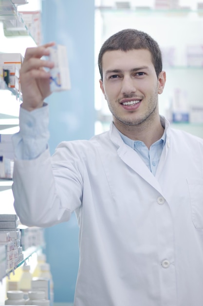 retrato de um belo jovem farmacêutico farmacêutico de pé na farmácia