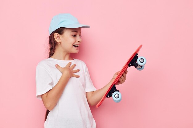 Retrato de um boné de menina feliz e sorridente no skate de camiseta branca Estilo de vida inalterado