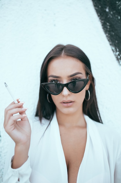 Foto retrato, de, um, bonito, menina jovem, fumando um cigarro, contra, parede