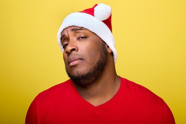 Foto retrato de um cara afro-americano com um chapéu de natal olhando arrogantemente direto para a câmera