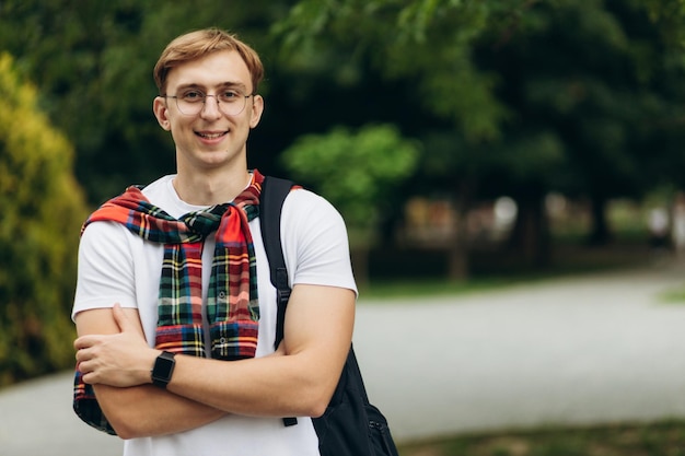 Retrato de um cara atraente em óculos de estudante com uma mochila Conceito de aprendizagem Copiar espaço