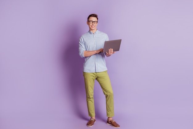 Retrato de um cara bonito programador freelancer segurando uma câmera de look pc em fundo violeta