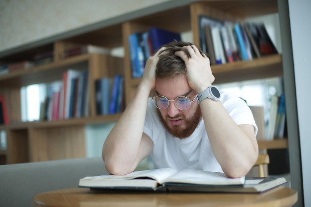 Retrato de um cara cansado e sobrecarregado, um jovem exausto em óculos de faculdade ou estudante universitário é