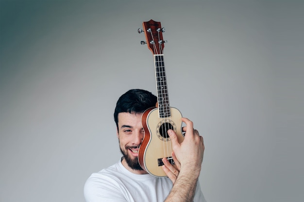 Retrato de um cara coberto com um pequeno ukulele