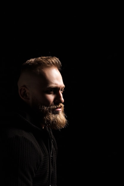 Retrato de um cara com barba no escuro