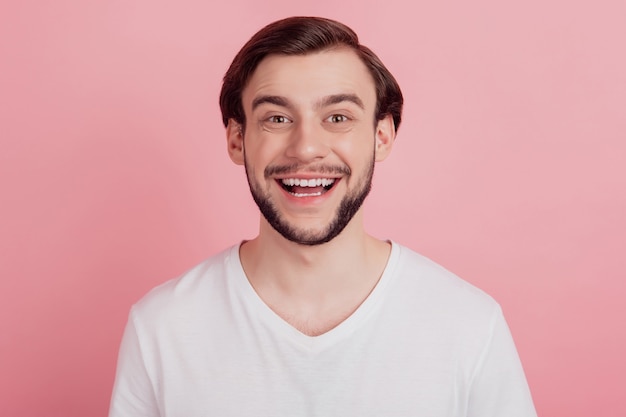 Retrato de um cara positivo engraçado e funky sonhador olha a câmera no fundo rosa