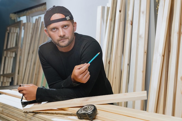 Retrato de um carpinteiro barbudo em roupas escuras enquanto trabalhava em sua oficina Fabricação de produtos artesanais de madeira
