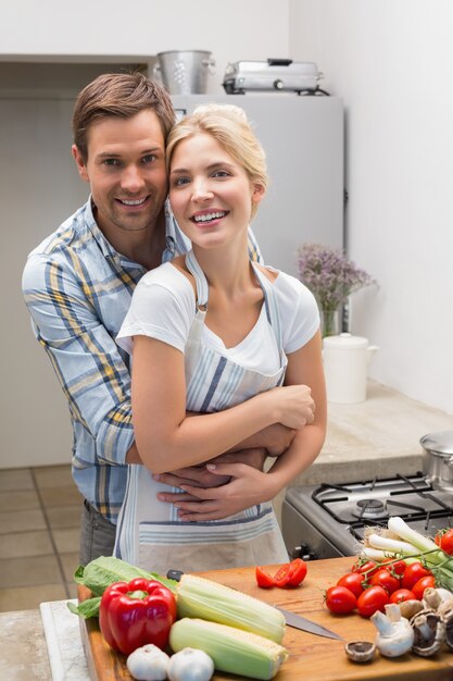 Retrato de um casal abraçando enquanto prepara comida na cozinha