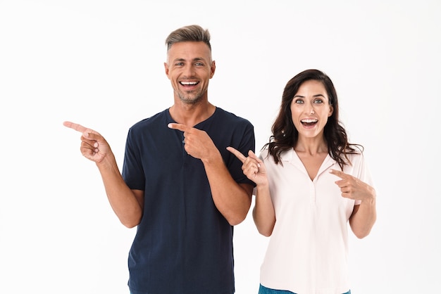 Foto retrato de um casal apaixonado adulto emocional chocado apontando isolado sobre uma parede branca.