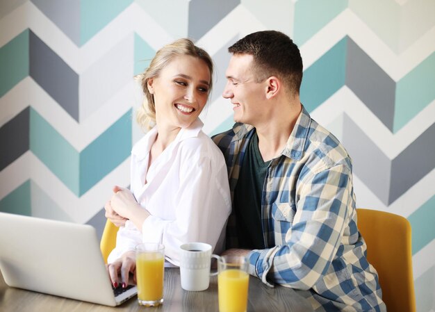 Retrato de um casal apaixonado rindo tomando café da manhã enquanto está sentado à mesa em uma cozinha