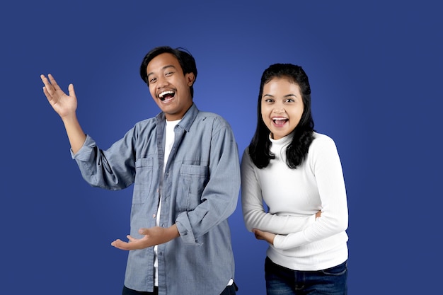 Retrato de um casal asiático incrível com um grande sorriso abrindo as mãos sobre fundo azul isolado