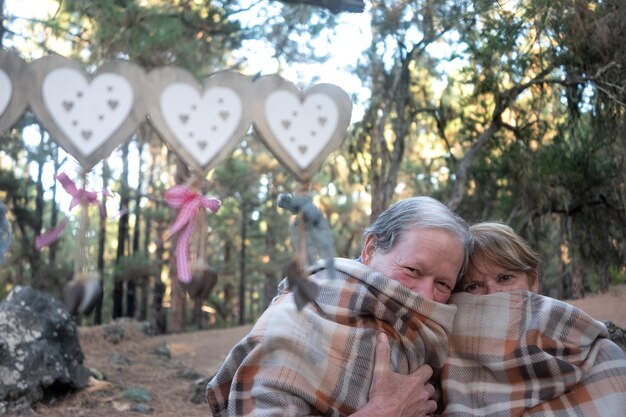 Foto retrato de um casal coberto por um cobertor na floresta