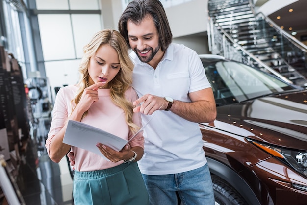 retrato de um casal com catálogo escolhendo um carro no salão da concessionária