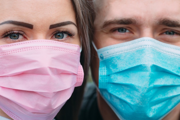 Foto retrato de um casal de aparência europeia com máscaras médicas.