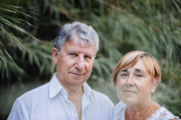 Foto retrato de um casal de idosos de pé contra plantas