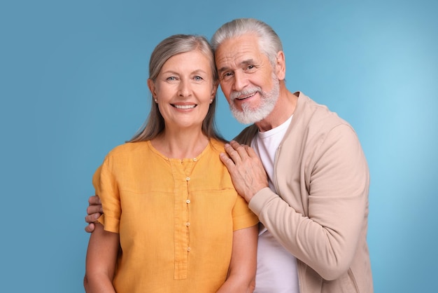 Retrato de um casal de idosos feliz e afetuoso em fundo azul claro