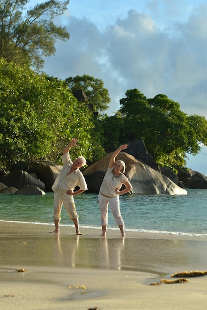 Retrato de um casal de idosos feliz na praia tropical se exercitando