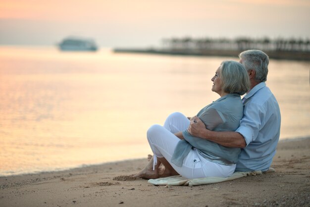 Retrato de um casal de idosos no mar ao pôr do sol