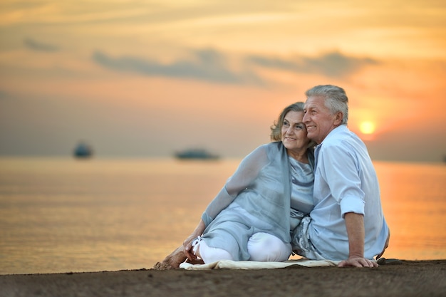 Retrato de um casal de idosos no mar ao pôr do sol