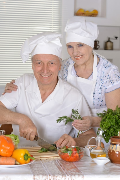 Retrato de um casal de idosos preparando salada de legumes juntos