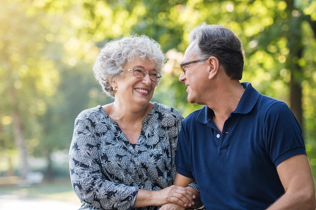 Foto retrato de um casal de idosos sorrindo e olhando um para o outro