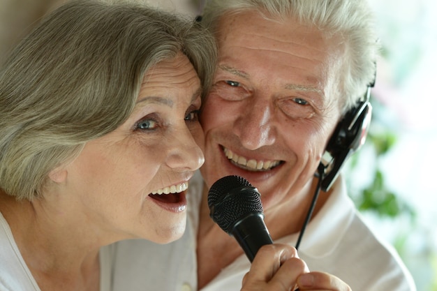 Retrato de um casal feliz de idosos cantando no microfone