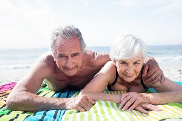 Retrato de um casal feliz de idosos, deitado na praia