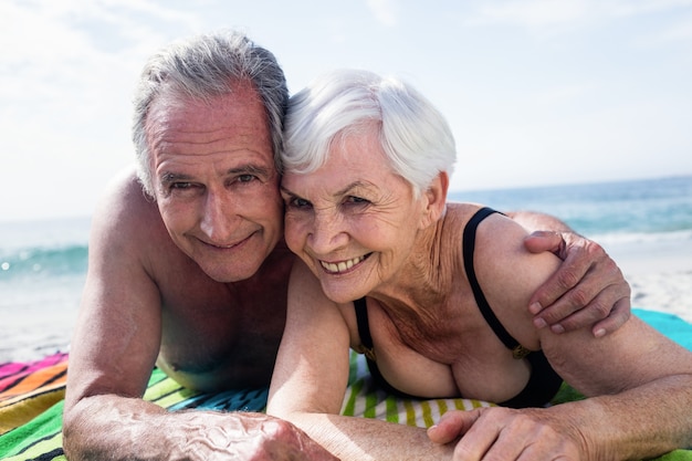 Retrato de um casal feliz de idosos, deitado na praia