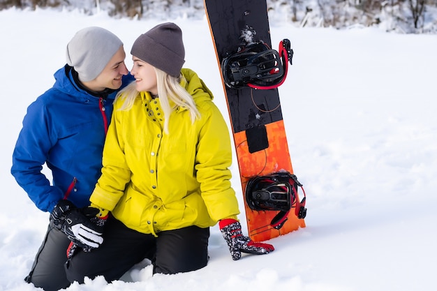 Retrato de um casal feliz de snowboarders do lado de fora durante as férias de inverno