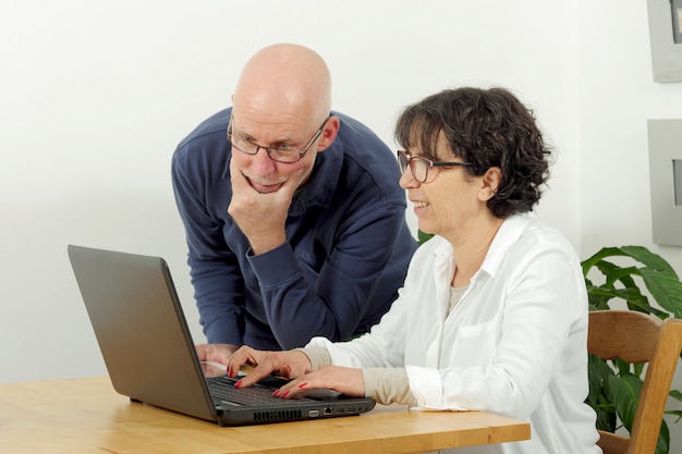 Retrato de um casal feliz sênior usando laptop