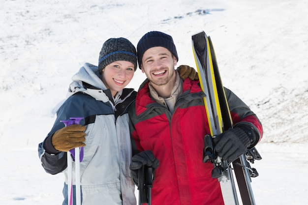 Retrato de um casal sorridente com placas de esqui na neve