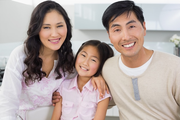 Retrato de um casal sorridente com uma filha na cozinha