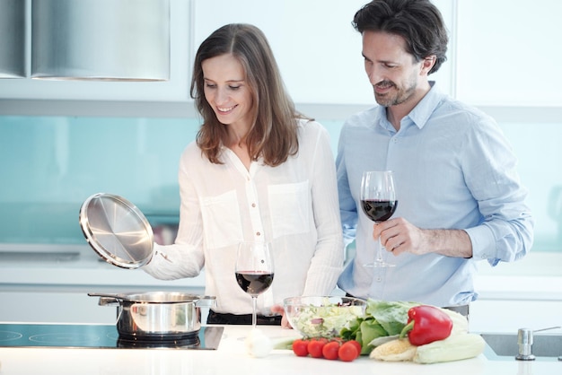 Retrato de um casal tomando um copo de vinho tinto enquanto cozinha o jantar