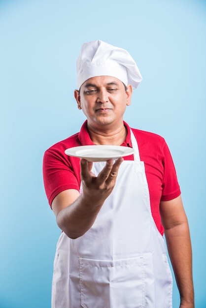 Retrato de um chef indiano bonito posando enquanto realiza atividades