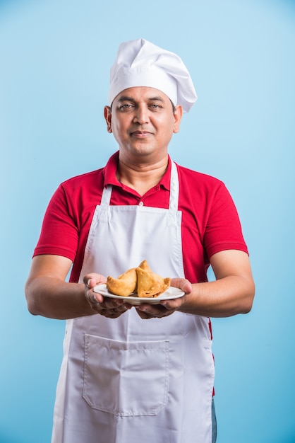 Retrato de um chef indiano bonito posando enquanto realiza atividades