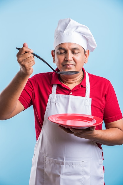 Retrato de um chef indiano bonito posando enquanto realiza atividades