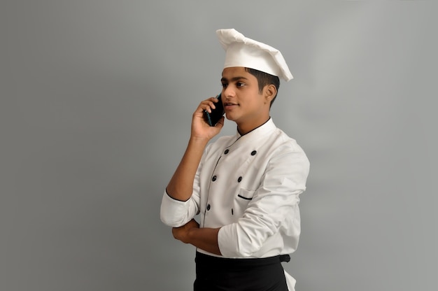 Retrato de um chef masculino feliz vestido de uniforme falando ao telefone