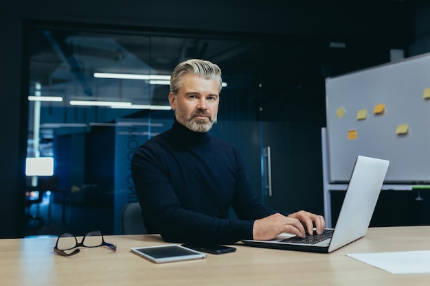 Retrato de um chefe sério de cabelos grisalhos olhando para a câmera pensando em um empresário maduro dentro do escritório